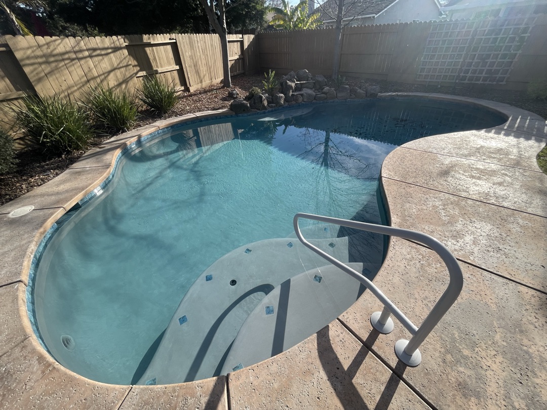 Same pool with fresh plaster, new step ledge, and rail after remodel