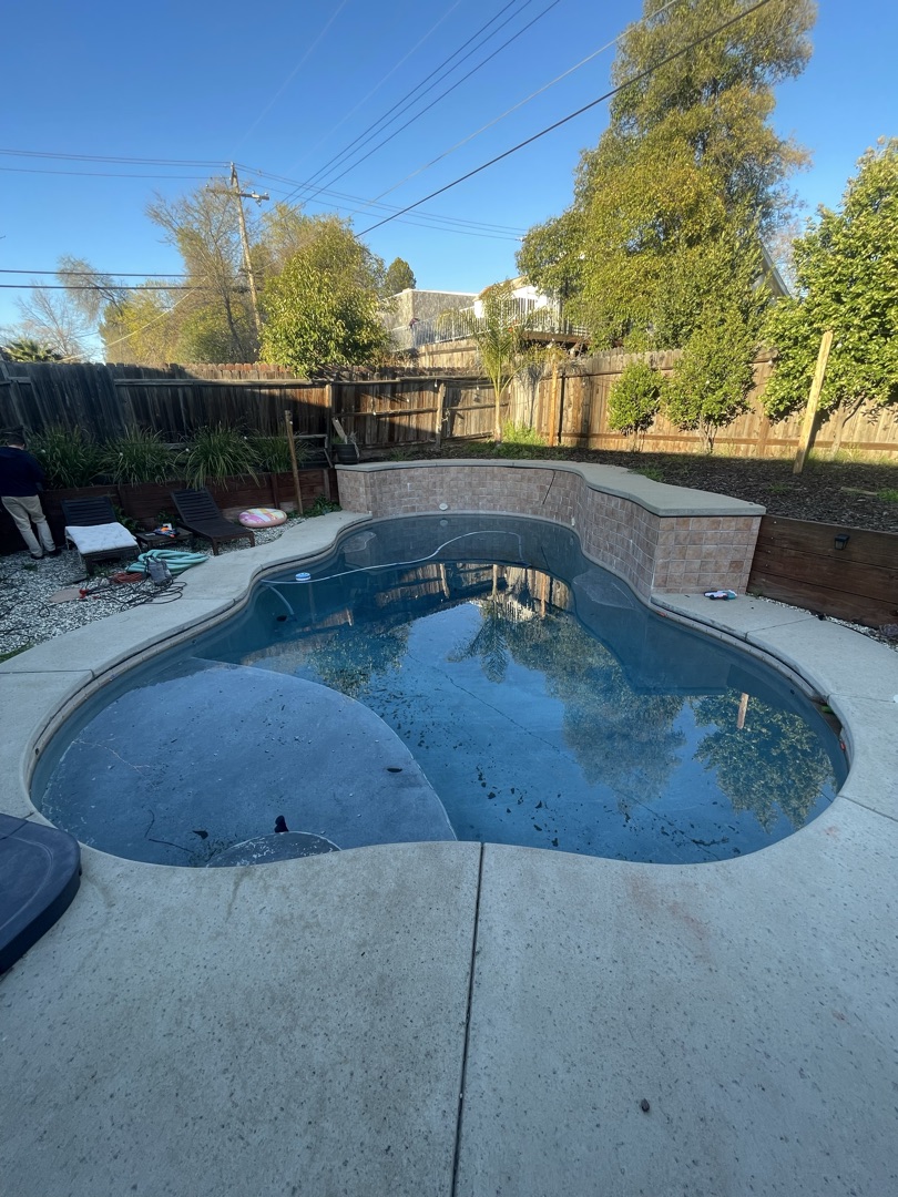 Drained pool with worn green tile waterline before renovation