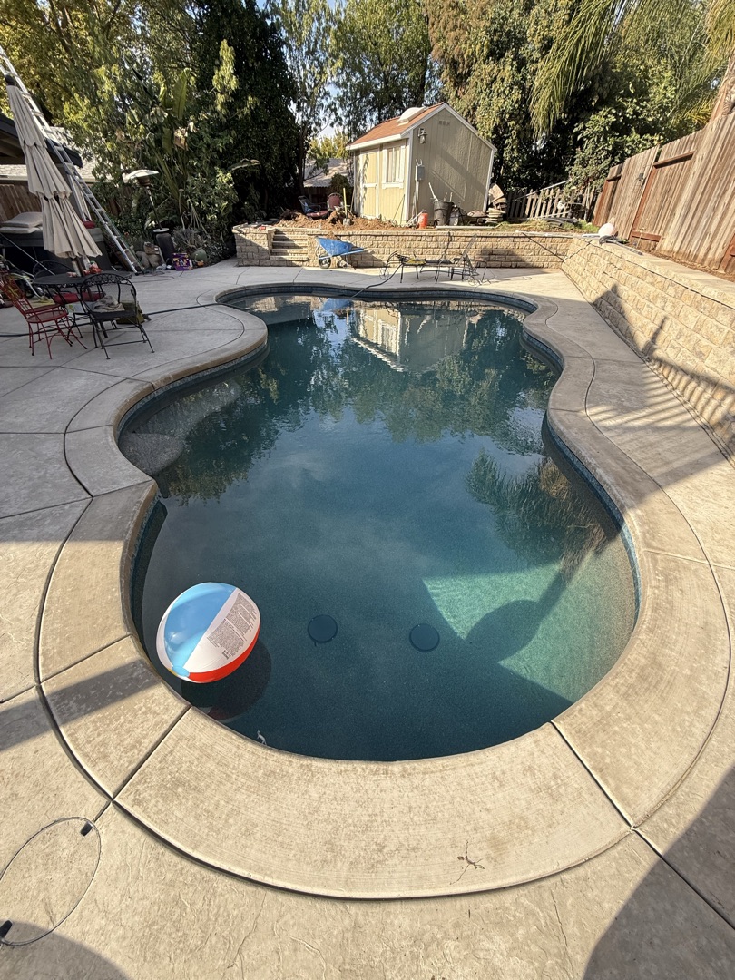 Finished freeform pool with stamped concrete deck and clear blue water